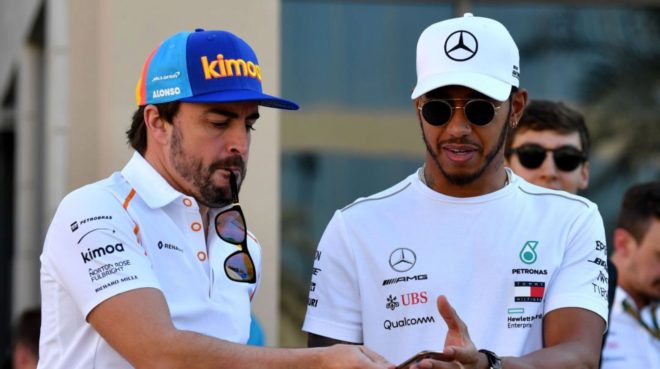 Alonso y Hamilton miran un celular.